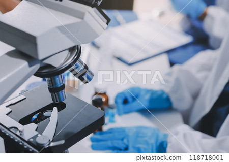Scientist using microscope in laboratory. Close-up of a researcher's hands adjusting a modern microscope in a lab setting. Science concept Scientist using microscope in laboratory. Close-up of a researcher's hands adjusting a modern microscope in a lab setting. Science concept 118718001