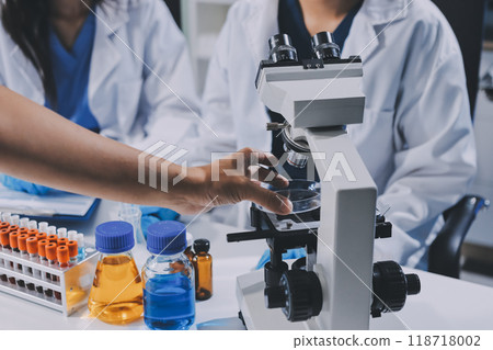 Scientist using microscope in laboratory. Close-up of a researcher's hands adjusting a modern microscope in a lab setting. Science concept Scientist using microscope in laboratory. Close-up of a researcher's hands adjusting a modern microscope in a lab setting. Science concept 118718002