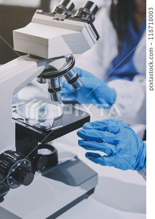 Scientist using microscope in laboratory. Close-up of a researcher's hands adjusting a modern microscope in a lab setting. Science concept Scientist using microscope in laboratory. Close-up of a researcher's hands adjusting a modern microscope in a lab setting. Science concept 118718003