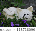Cute Stone Cat Sculpture Amidst Purple Flowers in Garden 118718090