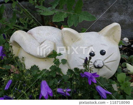 Cute Stone Cat Sculpture Amidst Purple Flowers in Garden Cute Stone Cat Sculpture Amidst Purple Flowers in Garden 118718090