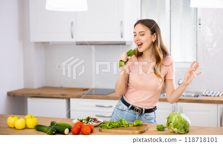 Happy housewife posing as singer at kitchen table Happy housewife posing as singer at kitchen table 118718101