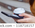 Hand holding smartphone and coffee cup with using applications in everyday life. 118718157