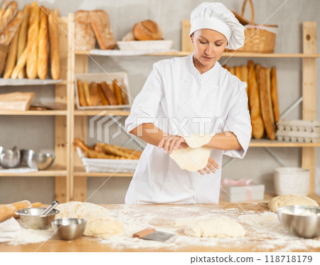 Woman works as baker in bakery, molds pies from dough, creates croissants from dough. 118718179