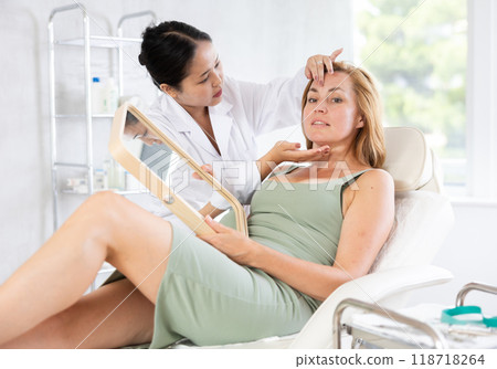 Professional cosmetologist talking about anti-aging skincare to patient Professional cosmetologist talking about anti-aging skincare to patient 118718264