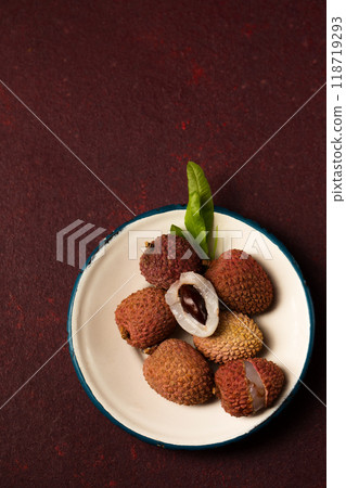 Small ripe lychee berries on a metal vintage plate on a burgundy background Small ripe lychee berries on a metal vintage plate on a burgundy background 118719293