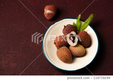 Small tropical lychee berries on a metal vintage plate on a burgundy background Small tropical lychee berries on a metal vintage plate on a burgundy background 118719294