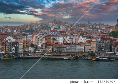 Vibrant view of Porto, Portugal, featuring the historic Ribeira district, Porto Cathedral, and traditional boats along the Douro River at dawn or dusk. Vibrant view of Porto, Portugal, featuring the historic Ribeira district, Porto Cathedral, and traditional boats along the Douro River at dawn or dusk. 118719897