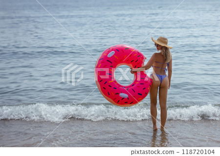 Athletic young woman with sexy athletic ass in bikini with inflatable swim ring. Outdoor lifestyle picture on a sunny summer day. Athletic young woman with sexy athletic ass in bikini with inflatable swim ring. Outdoor lifestyle picture on a sunny summer day. 118720104