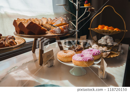 Elegant breakfast or dessert spread featuring pound cake, assorted donuts, and fresh oranges. Natural light enhances the sumptuous atmosphere in a luxury hotel. 118720150