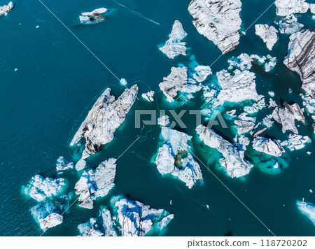 Stunning aerial view of clear turquoise waters with scattered white ice formations of various sizes and shapes, reflecting the sky in Iceland. 118720202