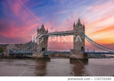Iconic Tower Bridge in London, UK, during a stunning sunset with pink, purple, and orange hues. The River Thames flows beneath, surrounded by modern and historic buildings. Iconic Tower Bridge in London, UK, during a stunning sunset with pink, purple, and orange hues. The River Thames flows beneath, surrounded by modern and historic buildings. 118720260