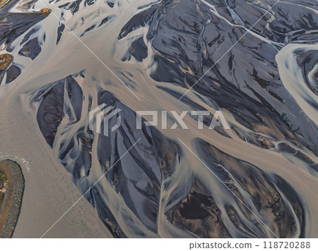 A stunning aerial view of a river delta in Iceland, showcasing light blue water branching into complex channels against a dark gray landscape. A stunning aerial view of a river delta in Iceland, showcasing light blue water branching into complex channels against a dark gray landscape. 118720288