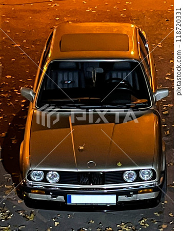 BMW E-30 in the parking lot is illuminated by street lights. Legendary car BMW E-30.Old BMW 3 series with angel eyes optics. 118720331