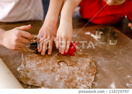 Close-up of children's hands cutting cookies with a cookie cutter on gingerbread dough 118720797