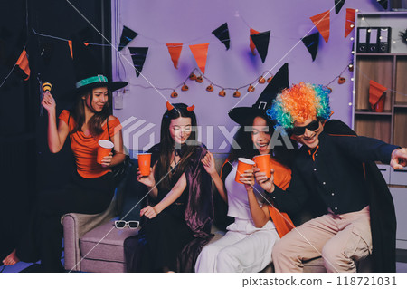 Joyful office Halloween party with coworkers in costumes, celebrating with drinks and laughter, fostering teamwork and festive spirit 118721031