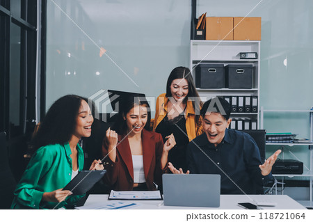 Young corporate employees sitting in office looking at laptop screen reading good news excited happy team diverse people celebrating victory win command success excellent result professional teamwork 118721064