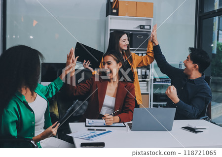Young corporate employees sitting in office looking at laptop screen reading good news excited happy team diverse people celebrating victory win command success excellent result professional teamwork 118721065