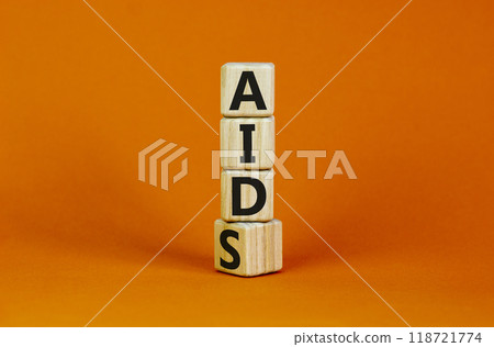 Symbol for helping people with aids, Acquired immunodeficiency syndrome. Turned a wooden cube with words aids aid. Beautiful orange background, copy space. Medical and aids aid concept. 118721774