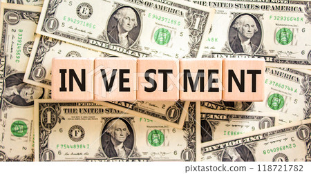 Investment symbol. Concept word Investment on beautiful wooden blocks. Dollar bills. Beautiful background from dollar bills. Business investment concept. Copy space. Investment symbol. Concept word Investment on beautiful wooden blocks. Dollar bills. Beautiful background from dollar bills. Business investment concept. Copy space. 118721782
