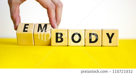 Body and embody symbol. Doctor turns wooden cubes and changes the concept word body to embody. Beautiful yellow table, white background, copy space. Medical, body and embody concept. 118721832