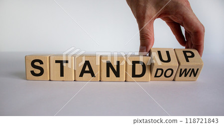 Hand turns a cube and changes the expression 'stand down' to 'stand up'. Business concept. Beautiful white background, copy space. 118721843