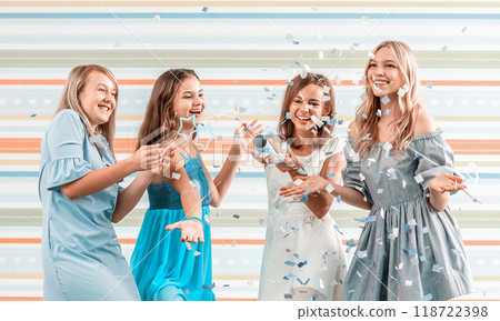 Smiling girls shoot confetti on striped background 118722398