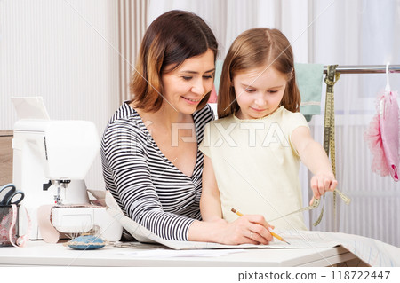 Master seamstress is teaching her pupil how to work with taken measurements 118722447