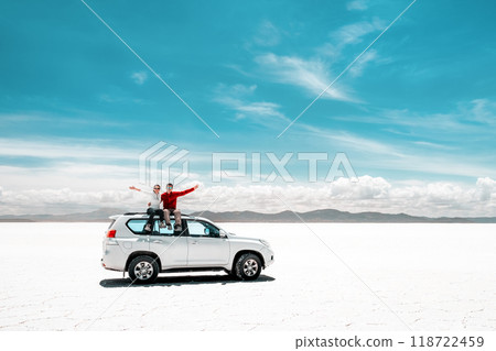 Pair of tourists sitting on white car in Salar de Uyuni Pair of tourists sitting on white car in Salar de Uyuni 118722459