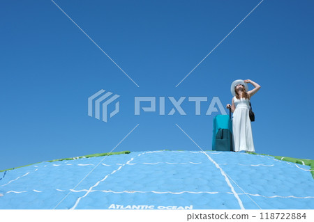 Girl with a suitcase woman traveler walking dragging a suitcase holding a passport and boarding pass. Background sky and airplane 118722884