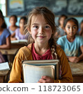 A young girl smiles brightly, holding a new textbook in a rural classroom. Wooden desks surround her as other girls learn, symbolizing the hope and excitement for equal education. 118723065
