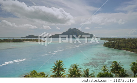Aerial drone footage of turquoise lagoon waters separating lush islets from volcanic mount Teurafaatiu on tropical Maupiti island. French Polynesia remote wild nature exotic summer travel background 118723119