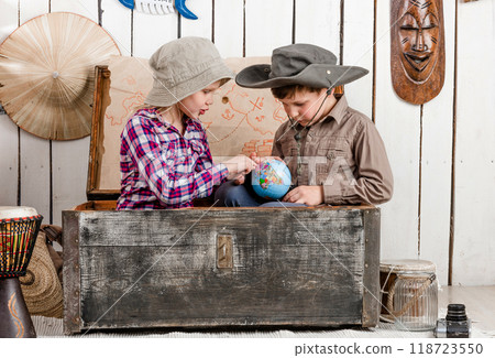little boy and girl study globe sitting in big old chest 118723550