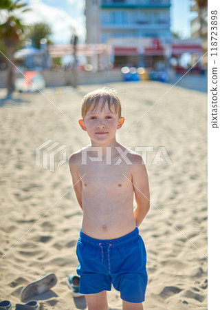 Refreshing Beach Adventure: Nine-Year-Old Boy Enjoying Sun-Soaked Coastal Paradise After Invigorating Swim in Crystal-Clear Mediterranean Waters. Carefree Summer Moments: Young Child Embracing Beach Refreshing Beach Adventure: Nine-Year-Old Boy Enjoying Sun-Soaked Coastal Paradise After Invigorating Swim in Crystal-Clear Mediterranean Waters. Carefree Summer Moments: Young Child Embracing Beach 118723898