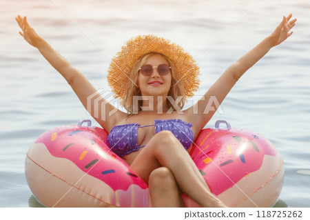 Beautiful young woman with inflatable donut in blue sea Beautiful young woman with inflatable donut in blue sea 118725262