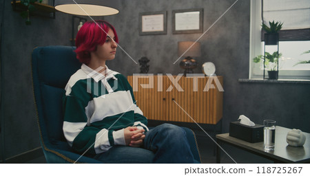 Upset girl sits in chair, discusses family problems with female psychotherapist Upset girl sits in chair, discusses family problems with female psychotherapist 118725267