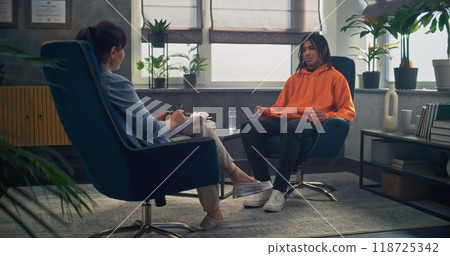 African American teen boy shares his feelings during counseling session with psychologist African American teen boy shares his feelings during counseling session with psychologist 118725342