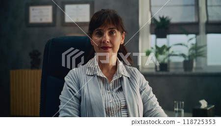 Stylish psychological office: Portrait of female therapist sitting in chair, looking at camera 118725353