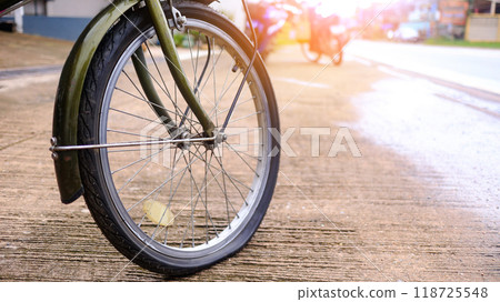 Flat tire wheel of bicycle parking on concrete sidewalk beside a road, need to be repaired, the moment of stillness and an unexpected pause in a journey. 118725548