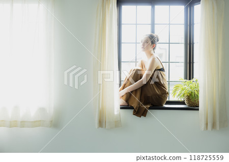 Woman sitting at a bay window 118725559