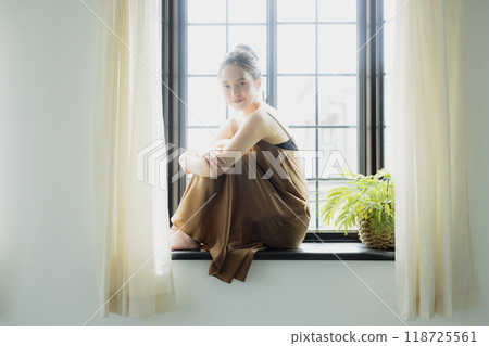 Woman sitting at a bay window Woman sitting at a bay window 118725561