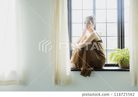Woman sitting at a bay window 118725562