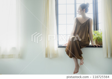 Woman sitting at a bay window Woman sitting at a bay window 118725564