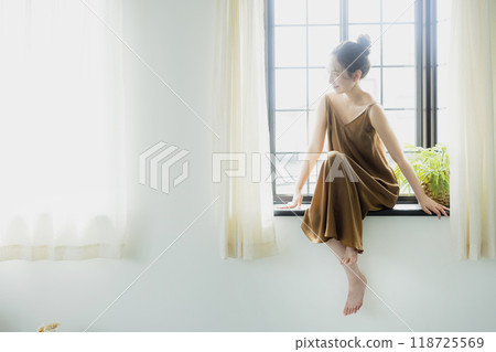 Woman sitting at a bay window Woman sitting at a bay window 118725569