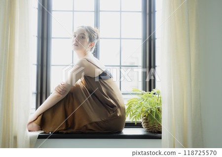 Woman sitting at a bay window 118725570