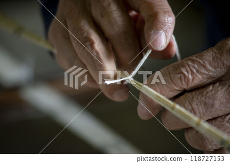 A craftsman tying threads for a kimono A craftsman tying threads for a kimono 118727153