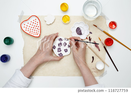 A woman paints clay products. Hobby clay modeling A woman paints clay products. Hobby clay modeling 118727759