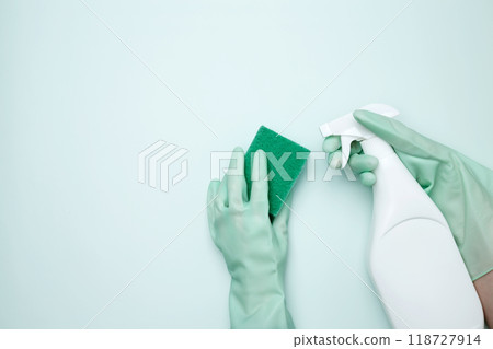 Womans hand in rubber glove holds green dishwashing sponge and cleaning product. House cleaning. Copy space Womans hand in rubber glove holds green dishwashing sponge and cleaning product. House cleaning. Copy space 118727914