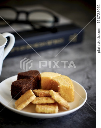 Sweets on a white plate, a white cup, a book and glasses 118728061