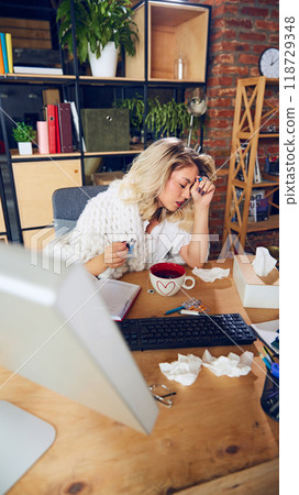 Overwhelmed worker takes moment to rest their head on desk. Feeling drained can come from both physical illness and mental exhaustion. 118729348